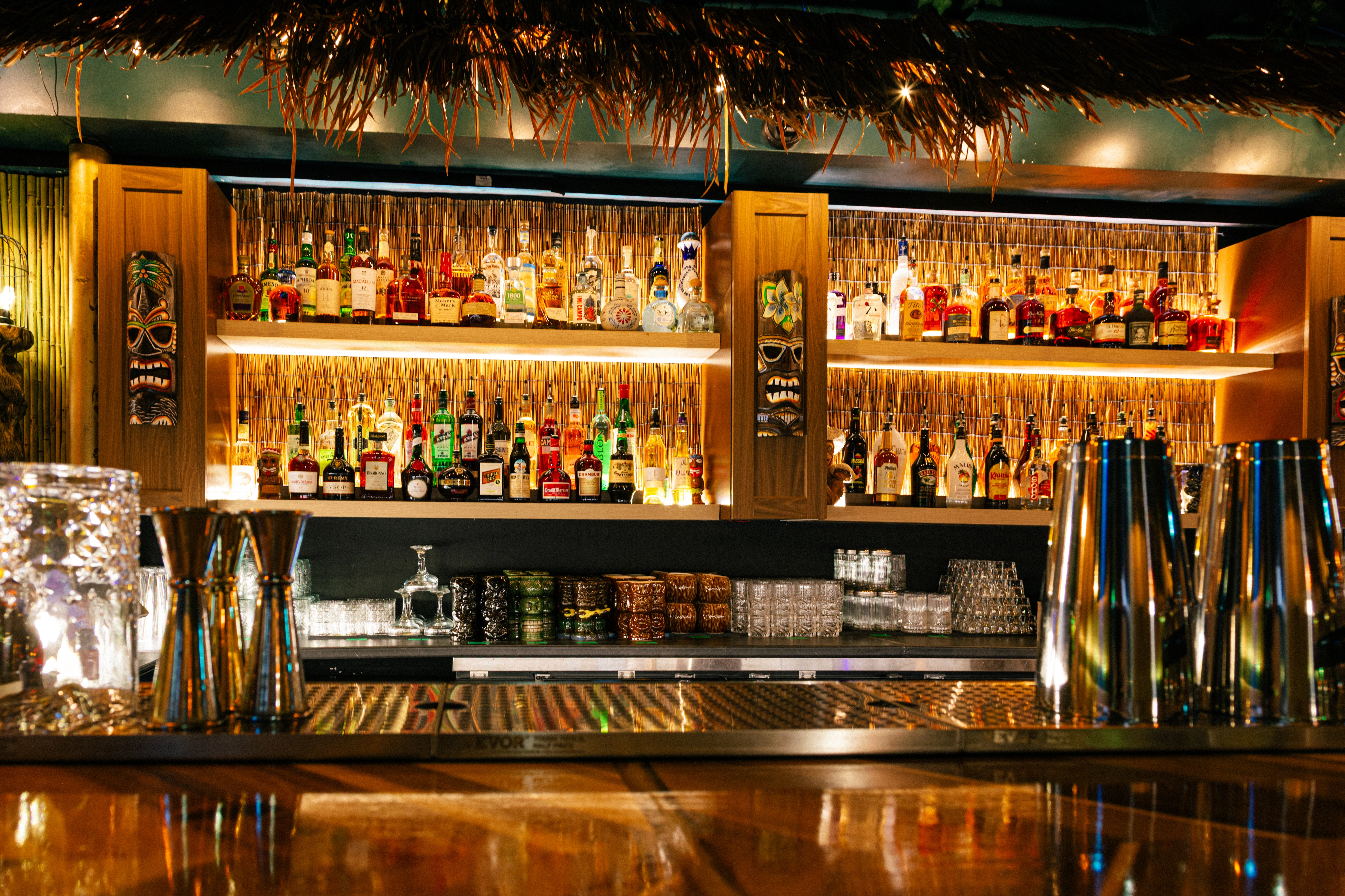 Inside Jungle Bird Tiki Lounge on 17th Ave Calgary with glowing tiki bar, bamboo textures, and tropical rum display